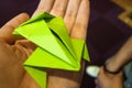 A green folded origami jumping frog on the hand.