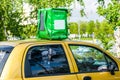 Green food delivery backpack standing on the top of yellow car. Mockup box for food delivery service. Copy space