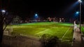 Green football field highlighted at night with trces of people running