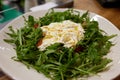 A green French bistro style salad with poached egg and chives on a white plate and table setting. Royalty Free Stock Photo