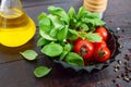 Green fresh leaves of organic basil and small ripe tomatoes, oil and pepper on a wooden background Royalty Free Stock Photo