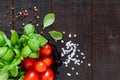 Green fresh leaves of organic basil and small ripe tomatoes and pepper on a wooden background Royalty Free Stock Photo