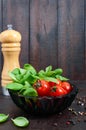 Green fresh leaves of organic basil and small ripe tomatoes and pepper on a wooden background Royalty Free Stock Photo