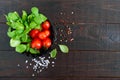 Green fresh leaves of organic basil and small ripe tomatoes and pepper on a wooden background for a healthy diet. Top view. Royalty Free Stock Photo