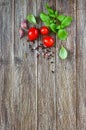 Green fresh leaves of organic basil and small ripe tomatoes salt and pepper on a wooden background Royalty Free Stock Photo