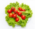 Green fresh lettuce leaves with juicy cherry tomatoes in a white bowl. Isolated on white background Royalty Free Stock Photo