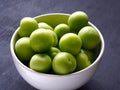 Green fresh plums in white bowl with black wood background Royalty Free Stock Photo