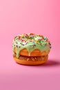 Green frosted donut with rainbow sprinkles on pink background Royalty Free Stock Photo