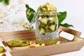 Green fruit smoothie layered in glass with chia seed pudding topped with star shaped banana and kiwi slices on wooden tray Royalty Free Stock Photo