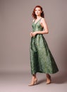 Green full-length evening dress. Beautiful model wearing emerald high heels, modern feminine look for an event