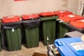 Green garbage bins with red lids in an apartment building waste area Royalty Free Stock Photo