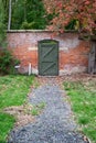 Green garden door at the end of a gravel path Royalty Free Stock Photo