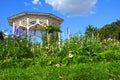 Green garden with flowers and a white gazebo Royalty Free Stock Photo