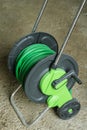 Green garden hose coiled on a spool in a cart. Garden hose cart. Royalty Free Stock Photo