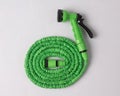 Green garden hose coiled with spray nozzle isolated Royalty Free Stock Photo