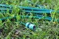 Green garden hose with fixture lying on the grass Royalty Free Stock Photo