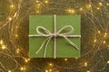 Green gift box and festive glowing lights on knitted background