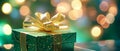 Green gift box with golden ribbon and bow on bokeh background. Christmas and New Year. Close-up blurred background Royalty Free Stock Photo