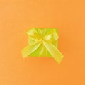 Green gift box on orange color background, square.