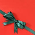 Green gift ribbon bow corner diagonal red paper background Royalty Free Stock Photo