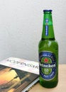 Green glass bottle of Heineken beer and book.