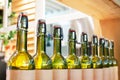 Green glass bottles of wine in line on wood shelf, bar interior design winery production, blurred background close up