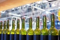 Green glass bottles of wine in row on wood shelf, bar interior design, preparation of alcoholic cocktails, wine tasting concept Royalty Free Stock Photo