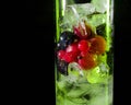 Green Glass of ice with berry gooseberries red black currants and water. Refreshing cocktail. Summer drink. Royalty Free Stock Photo