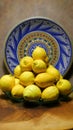 Green glass plate full of lemons with a Sicilian painted plate in the background