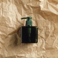 Green glass soap dispenser bottle on crumpled paper, top view