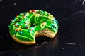 Green glazed donut with sprinkles isolated. Close up of colorful bitten donut Royalty Free Stock Photo