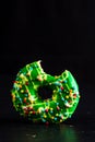 Green glazed donut with sprinkles isolated. Close up of colorful bitten donut Royalty Free Stock Photo