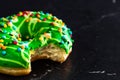 Green glazed donut with sprinkles isolated. Close up of colorful bitten donut Royalty Free Stock Photo