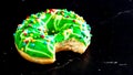 Green glazed donut with sprinkles isolated. Close up of colorful bitten donut Royalty Free Stock Photo