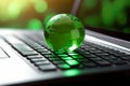 Green globe on a laptop keyboard with green bokeh background Royalty Free Stock Photo