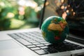 Green globe on laptop keyboard with bokeh background Royalty Free Stock Photo