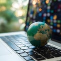 Green globe on laptop keyboard with bokeh background Royalty Free Stock Photo