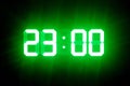 Green glowing digital clocks in the dark show 23:00 time