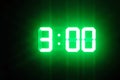 Green glowing digital clocks in the dark show 3:00 time