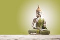 Green and golden Buddha statue, on sand in green background. .Meditation, spirituality and zen concept