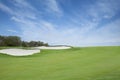 Green golf fairway with sand traps below blue sky with clouds Royalty Free Stock Photo