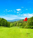 Green golf field and blue sky. Golf course red flag Royalty Free Stock Photo