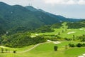 A green golf field in the valley and mountains background at Shenzhen Overseas Chinese Town East OCT East in Guangdong, China. A