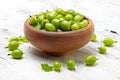 Green gooseberries in a ceramic bowl on an old wooden table Royalty Free Stock Photo