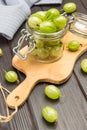 Green gooseberries in glass jar on cutting board Royalty Free Stock Photo