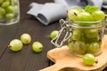 Green gooseberries in glass jar on cutting board Royalty Free Stock Photo