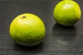 Green grapefruit on a wooden dark table.