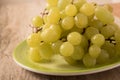 Green grapes in a plate on an old wooden background. Royalty Free Stock Photo