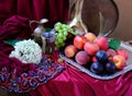 Green grapes, plums, peaches, nectarines, jugs, a glass of wine, white hydrangea, a Dutch still life on a silk tablecloth, with