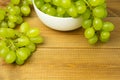 Green grapes in white ceramic bowl on wooden table with empty space
